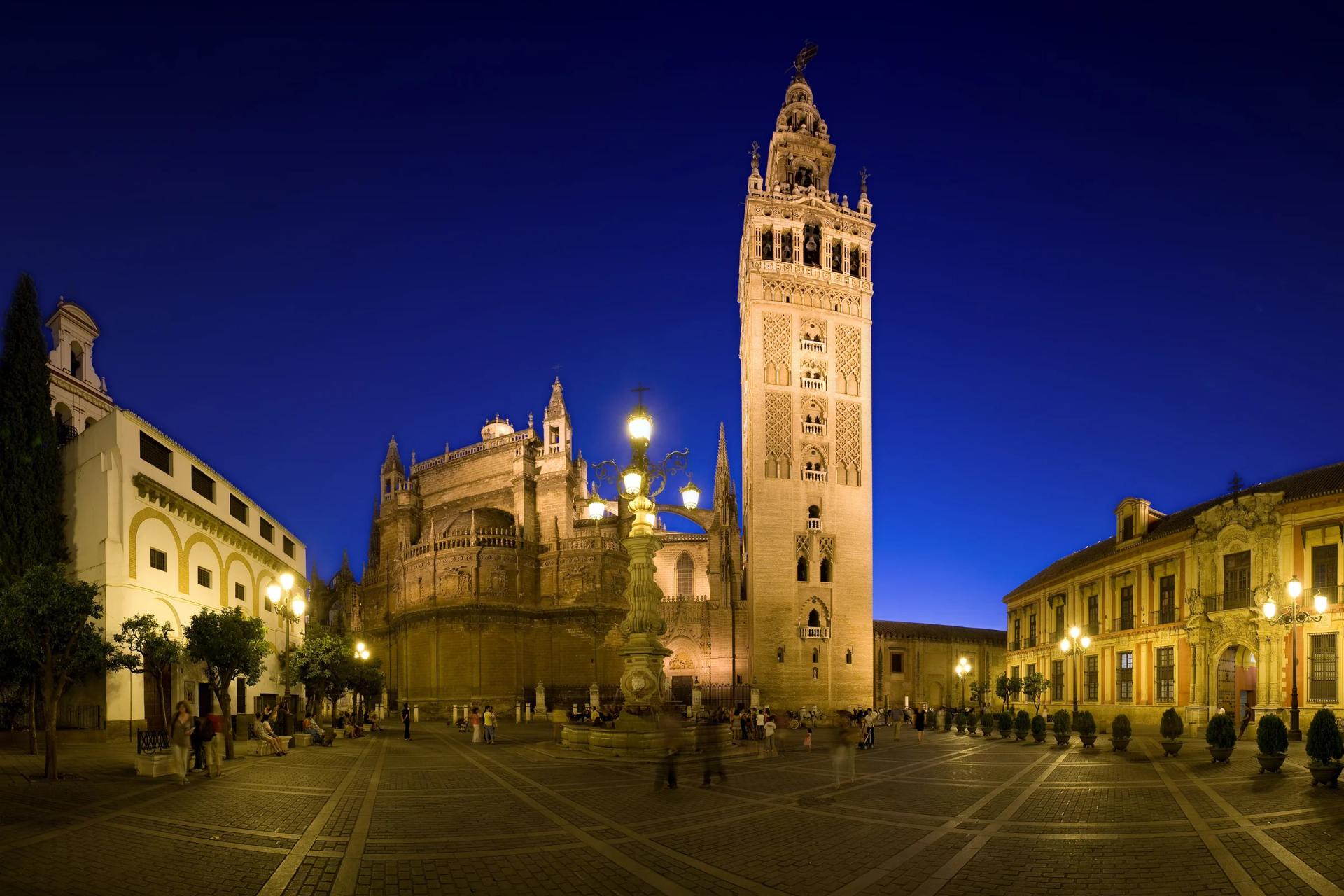La Catedral y la Giralda iluminadas al anochecer desde la plaza Virgen de los Reyes