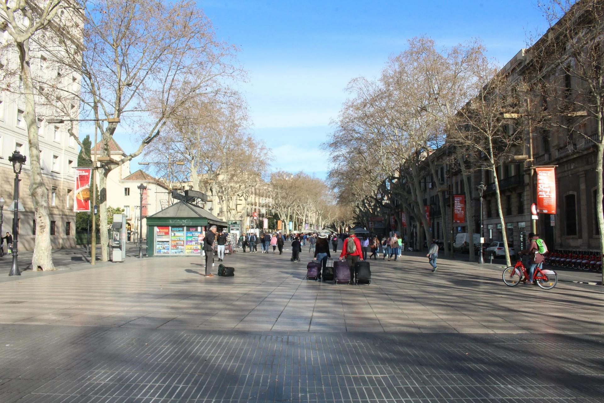 El paseo central de La Rambla, bajo los plátanos, con un quiosco y gente paseando