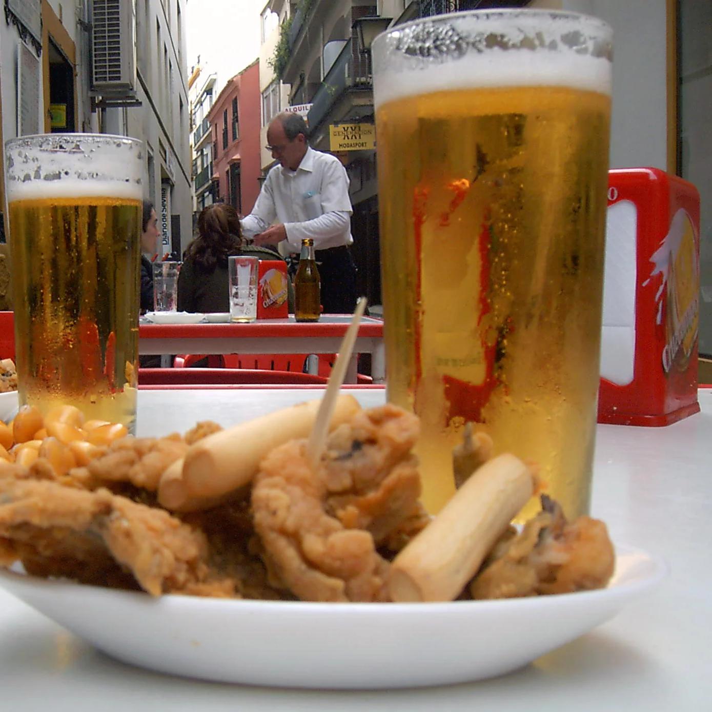 Plato de boquerones fritos con dos cañas en una terraza de Sevilla